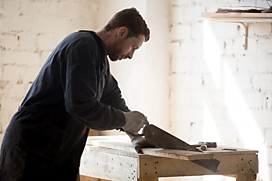 Мастер нарезает детали для деревянного стола